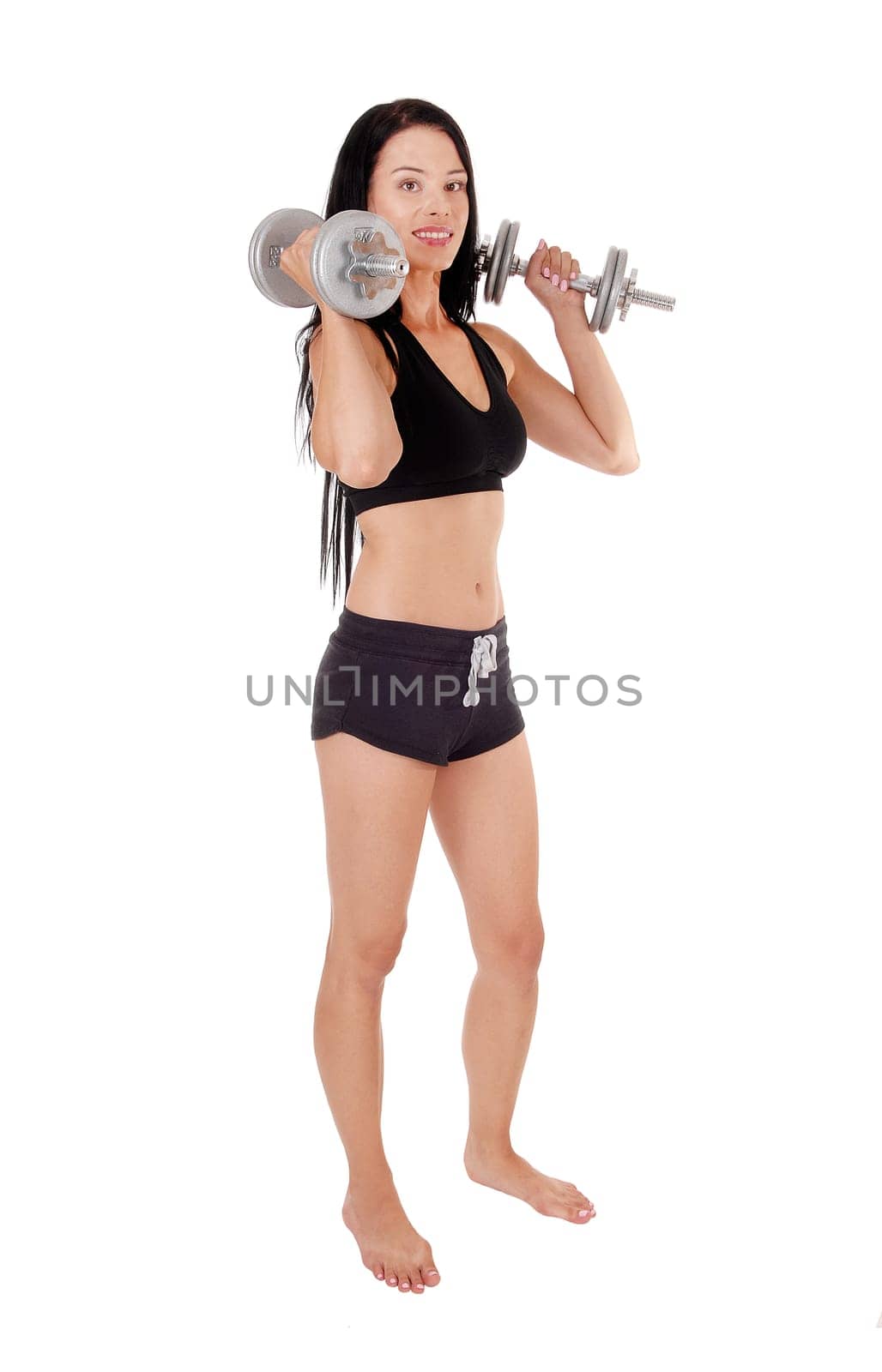 A gorgeous young woman with hair standing in profile with.two dumbbells, exercising for strengths, isolated for white background.