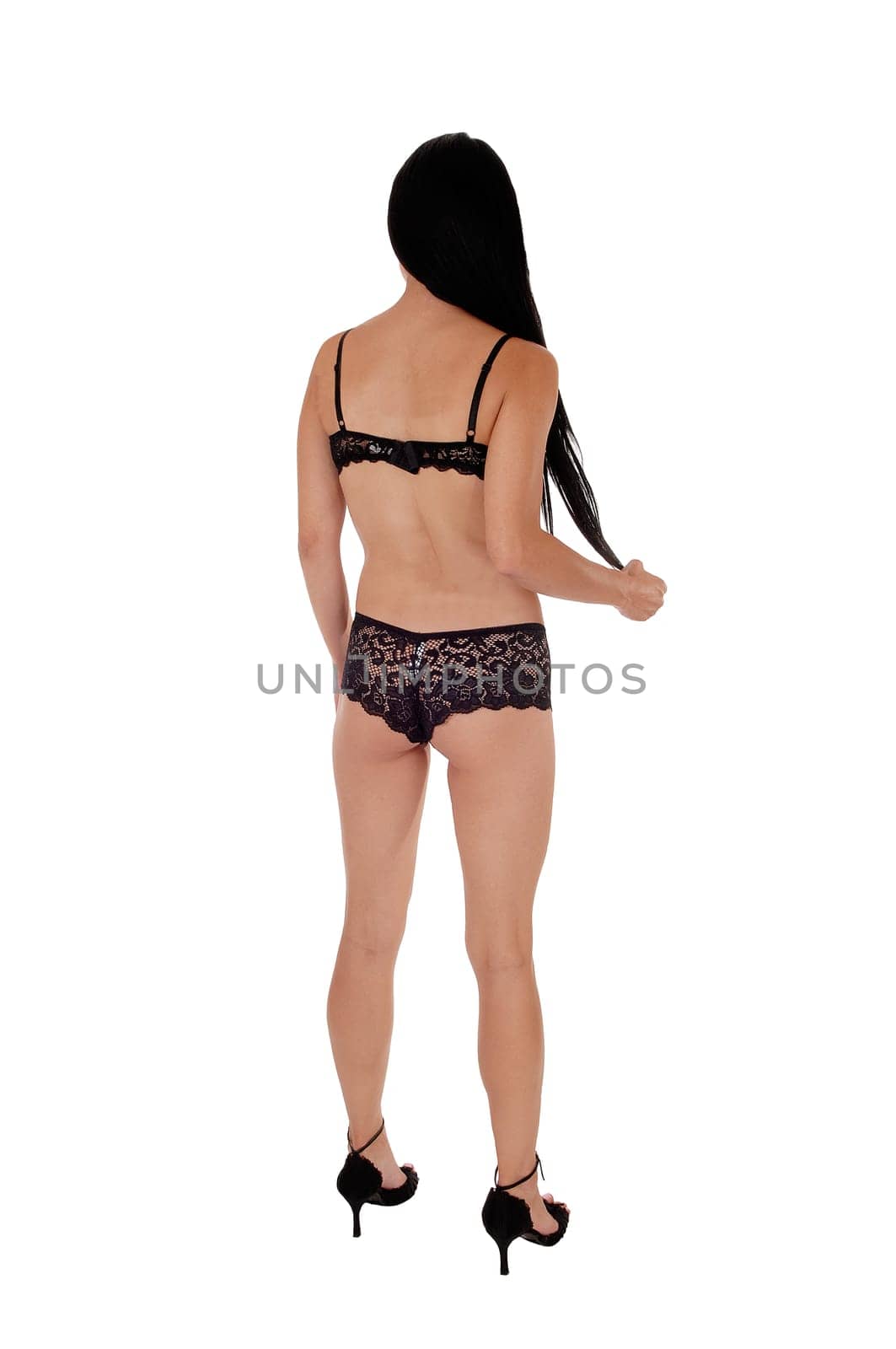 An tall slim woman standing from the back in her black lingerie with.her long black hair and heels, isolated for white background.