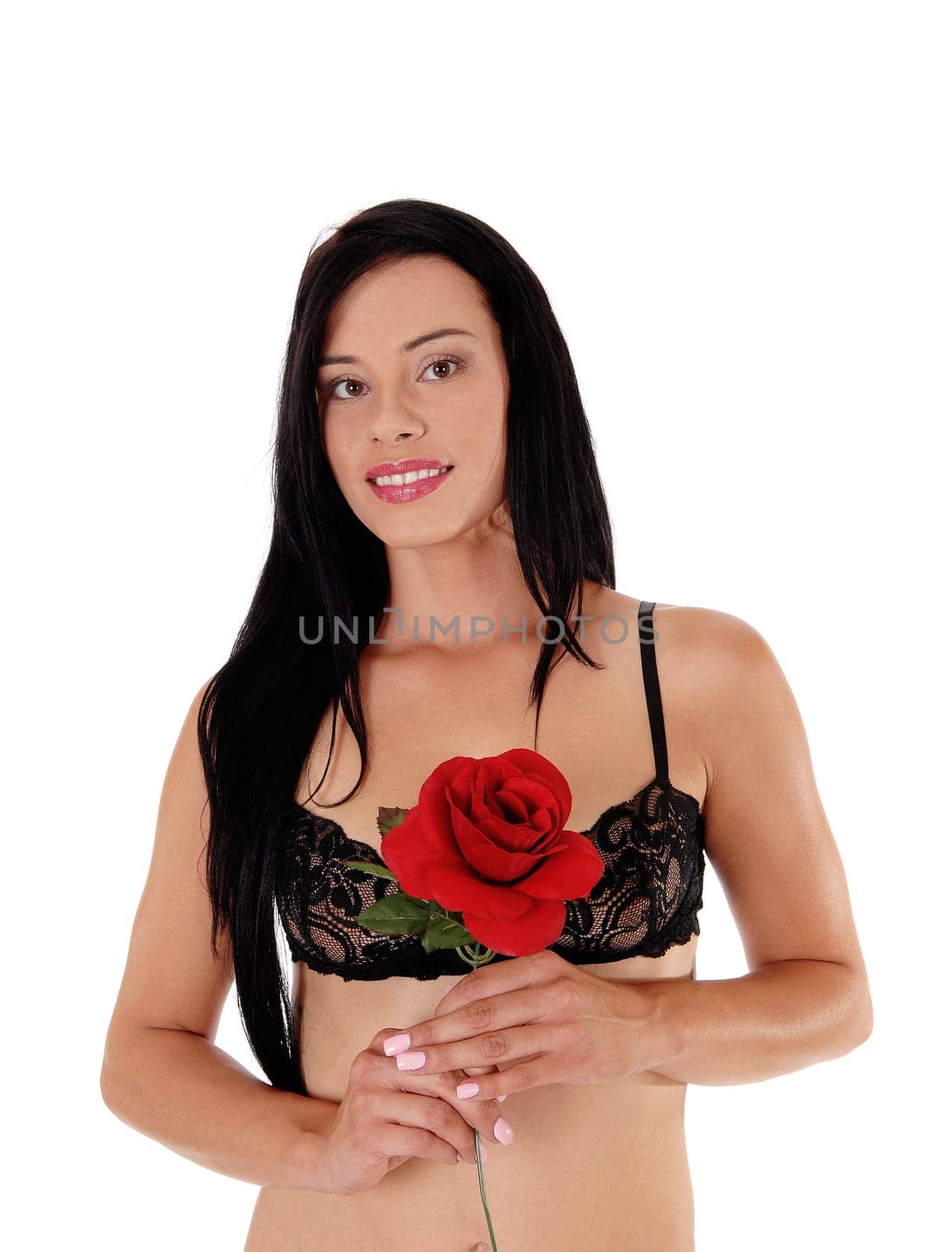 A lovely young woman standing in a portrait image waist up in a black.bra, looking into the camera, with red rose, isolated for white background.