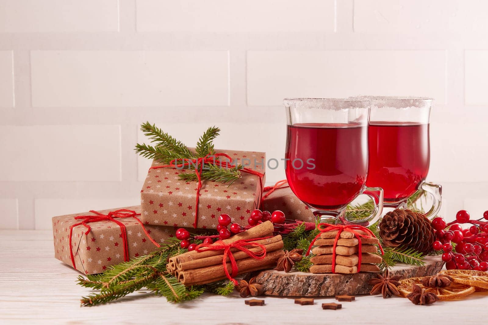 Still life with glasses of mulled wine or fruit tea, gift boxes, gingerbread cookies and christmas decorations on a wooden table. Christmas and New Year treat.