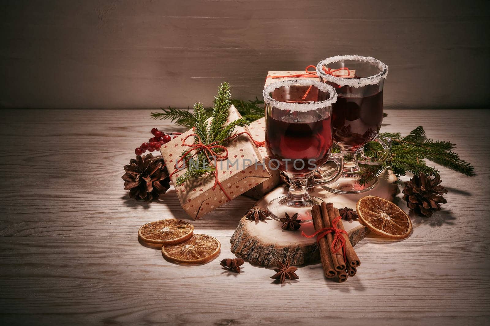 Still life with glasses of mulled wine or fruit tea, gift boxes and christmas decorations on a wooden table. New year and Christmas.