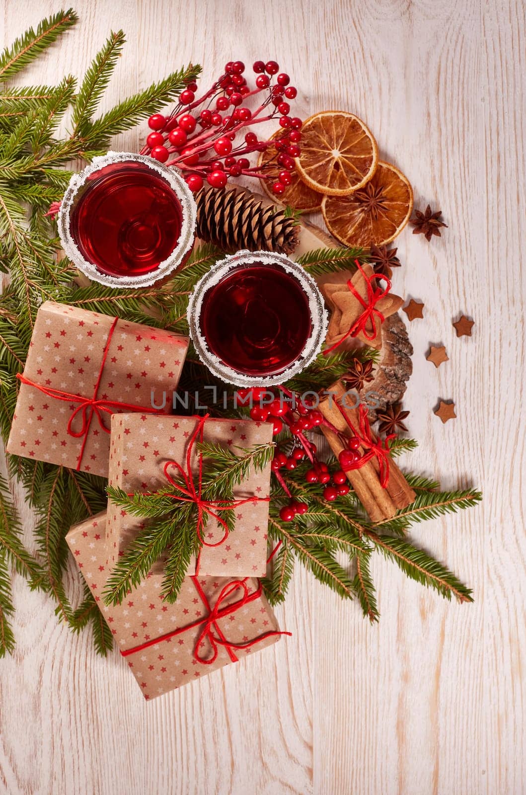 Still life with glasses of mulled wine or fruit tea, gift boxes, gingerbread cookies and christmas decorations on a wooden table.Top view. Christmas and New Year treat.