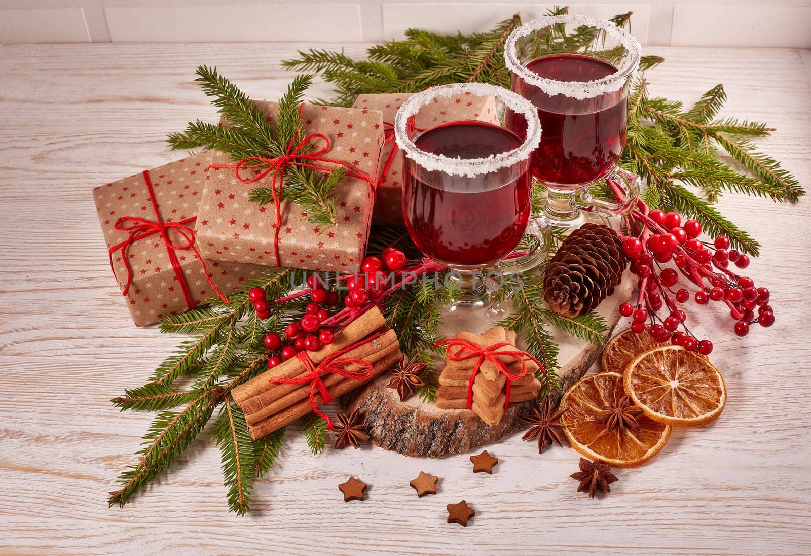 Still life with glasses of mulled wine or fruit tea, gift boxes, gingerbread cookies and christmas decorations on a wooden table. Christmas and New Year treat.