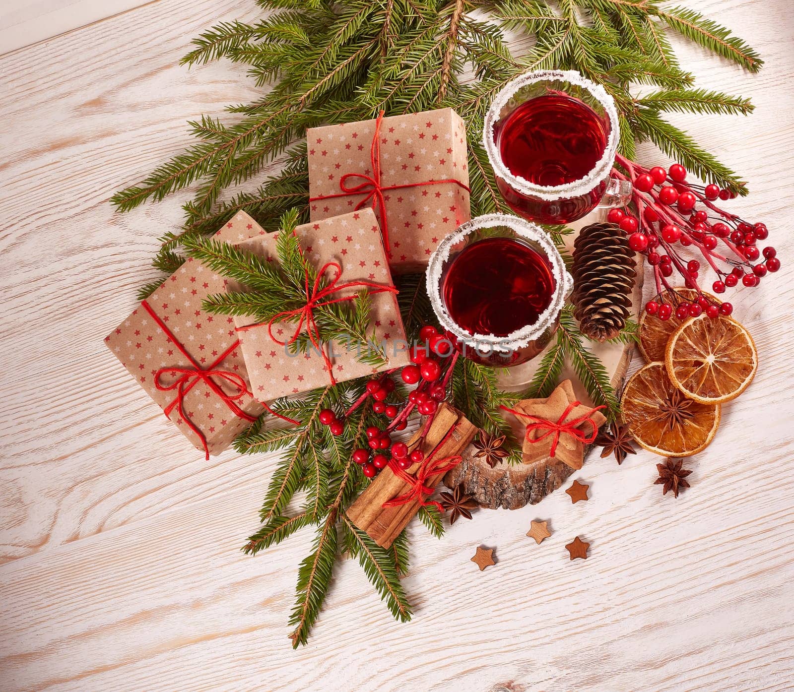 Still life with glasses of mulled wine or fruit tea, gift boxes, gingerbread cookies and christmas decorations on a wooden table.Top view. Christmas and New Year treat.