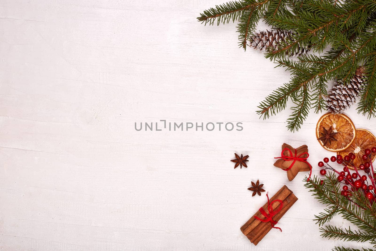 Fir branches, cones and gingerbread cookies on a white wooden background. Top view with copy space. New Year and Christmas