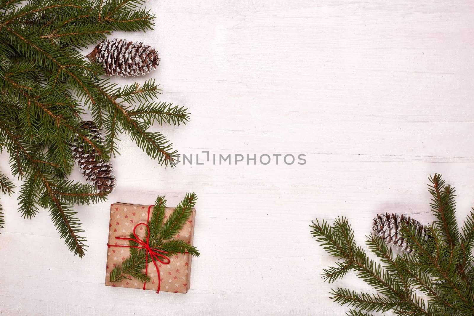 Fir branches, cones and gift box on a white wooden background. Top view with copy space. New Year and Christmas