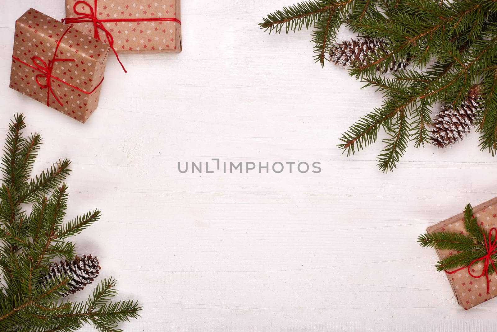 Fir branches, cones and gift boxes on a white wooden background. Top view with copy space. New Year and Christmas