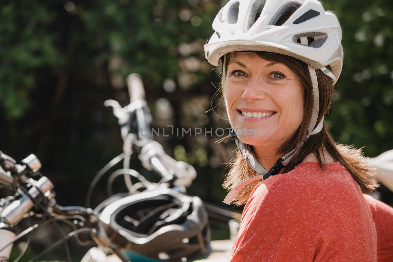 Headshot of a mature female wearing a cycling helmet and looking at the camera and smiling.