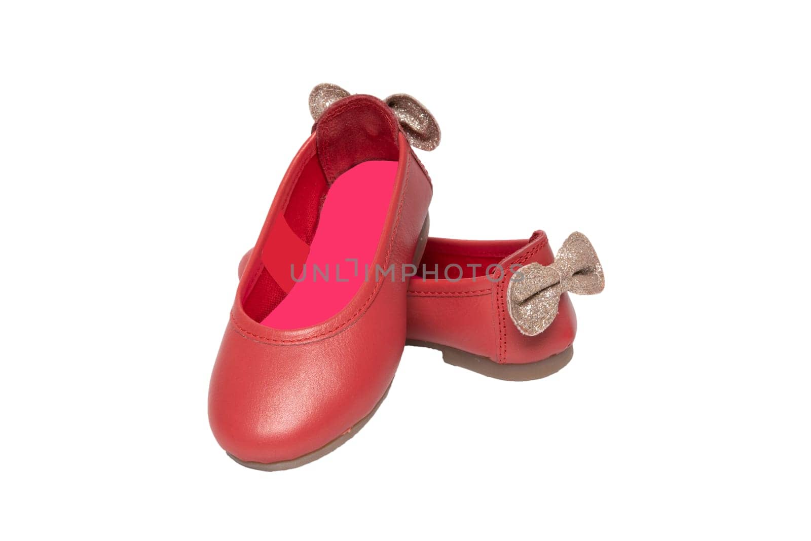 Red shoes. Closeup of red girls shoes with a golden bow isolated on a white background. Fashionable footwear.