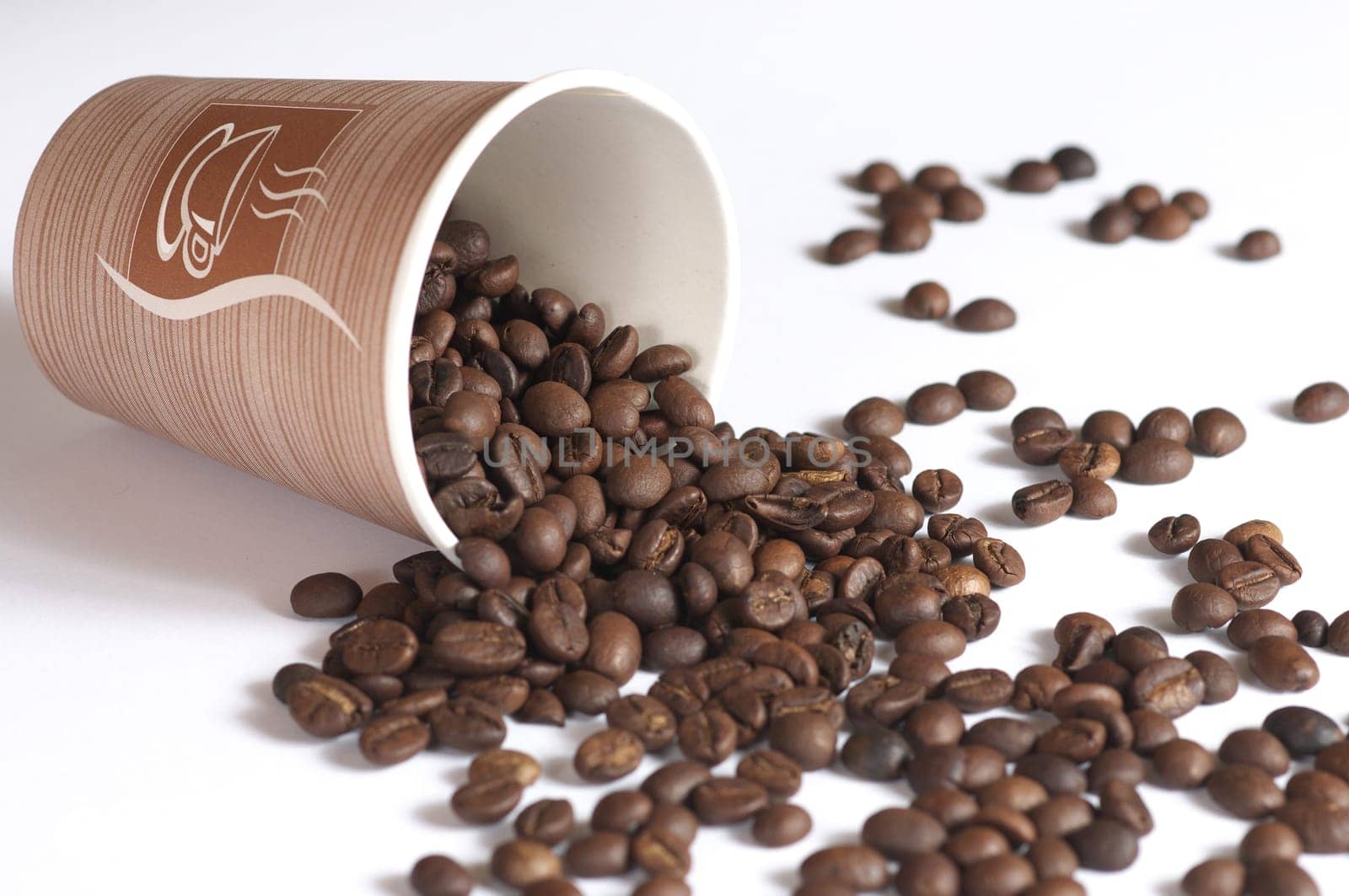 Dropped coffee beans. Coffee beans dropped into the paper. Glass with coffee beans dropped on white background.