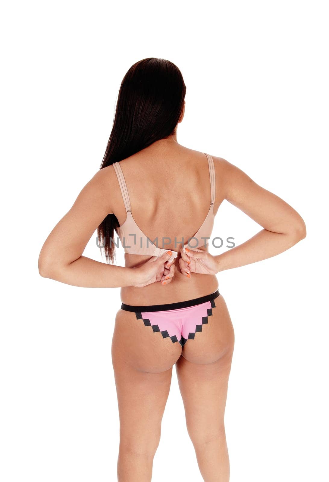 A young gorgeous woman standing from the back in lingerie panties,.taking of her beige bra, isolated for white background.