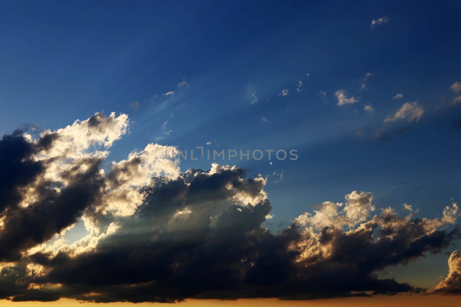 At sunset the sun shines through dark and bright clouds
