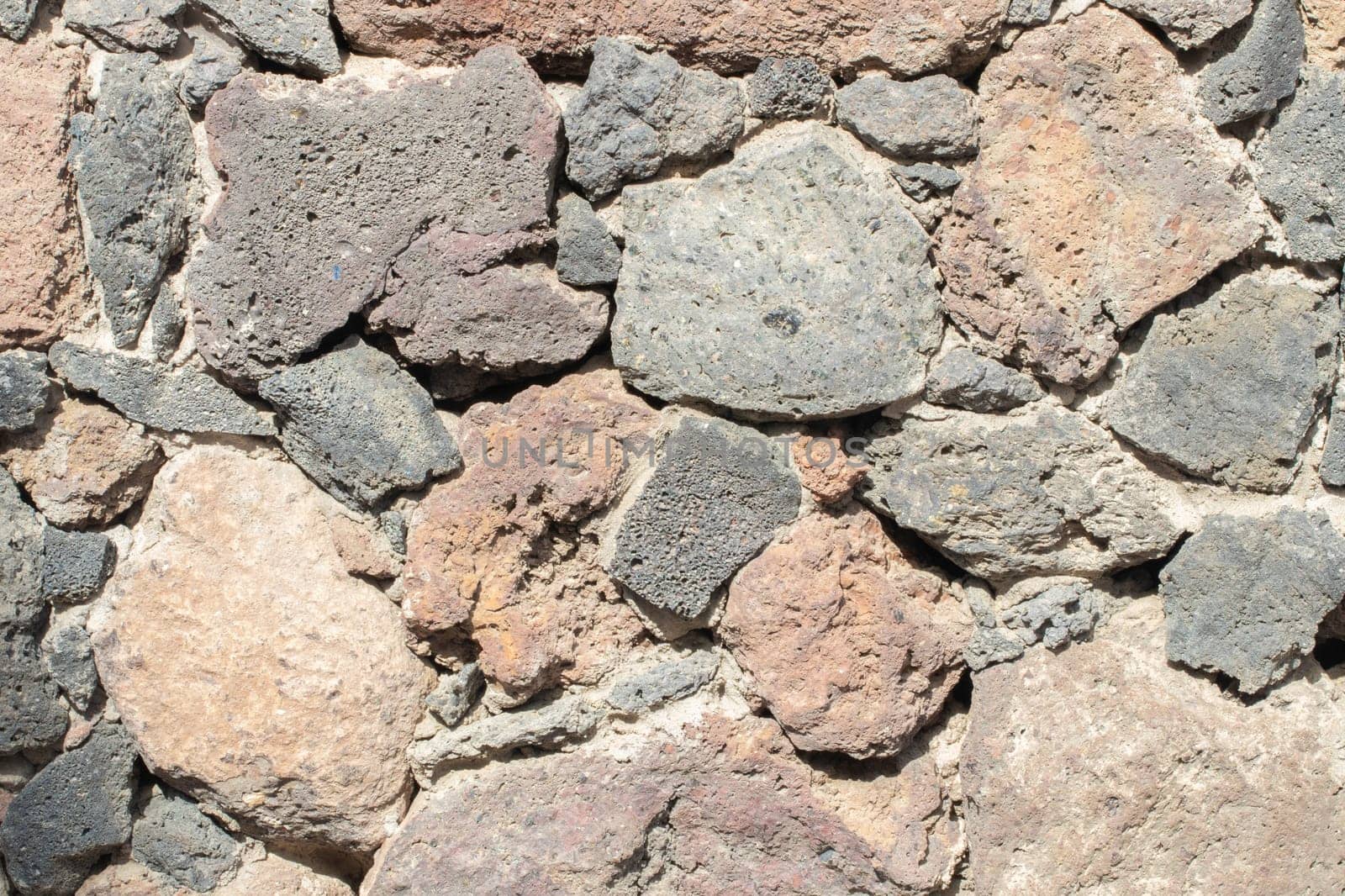 Stone texture background. Close-up of stone wall fragment with colorfull surface as rock wall texture for designer.