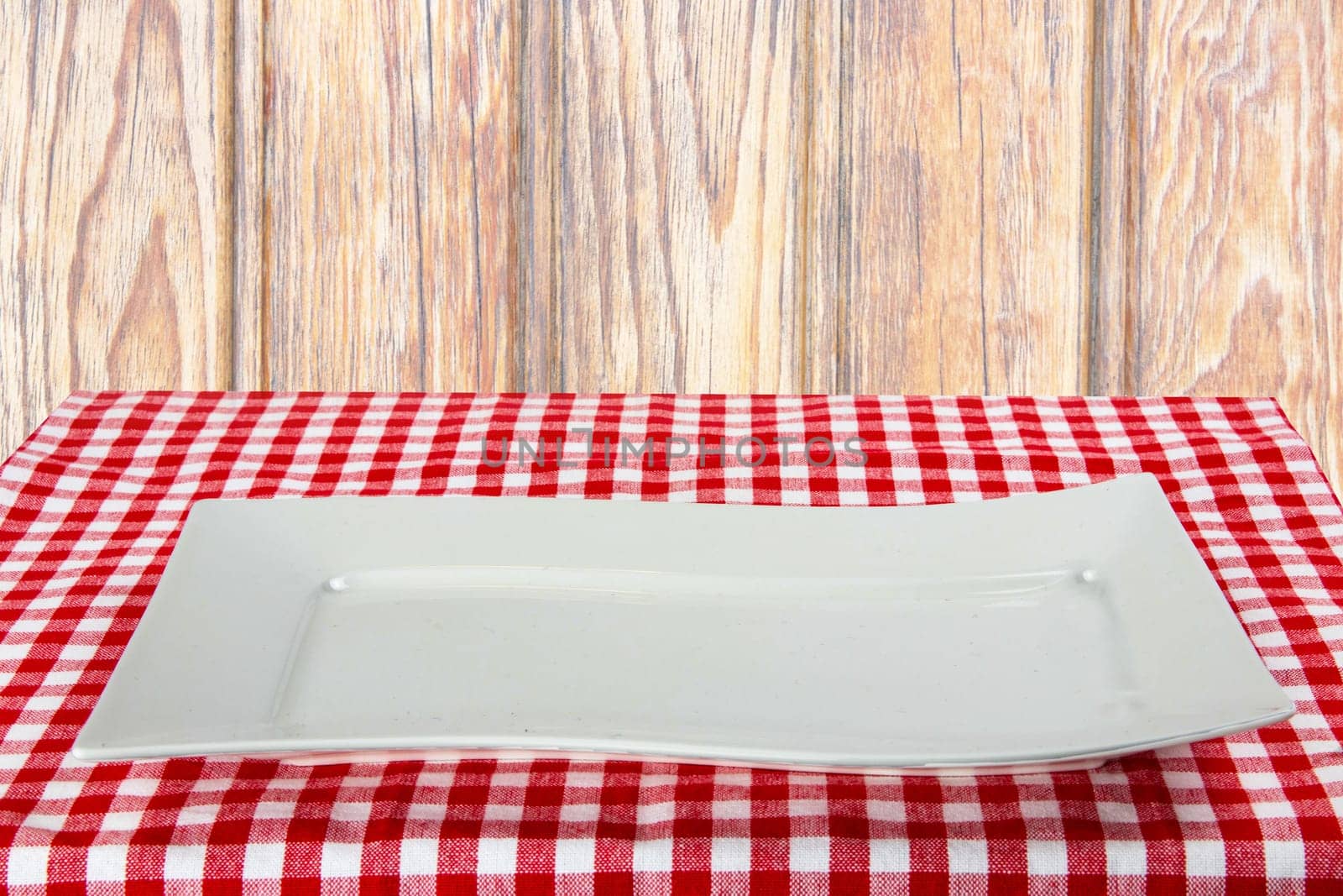 Empty white plate on red napkin over wooden background. For your food and product display montage. Concept food. Copy space.