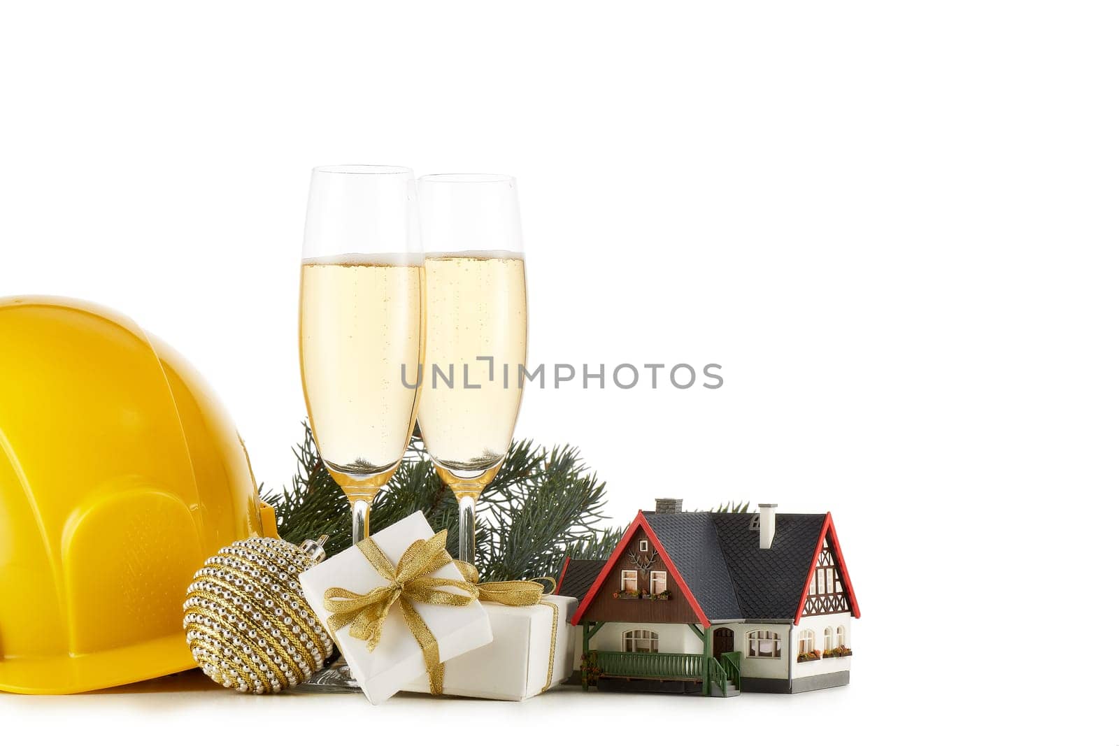 Construction hard hat, fir tree branches, model house, two glasses with champange and Christmas ornament isolated on a white background. New Year and Christmas. Horizontal view with copy space