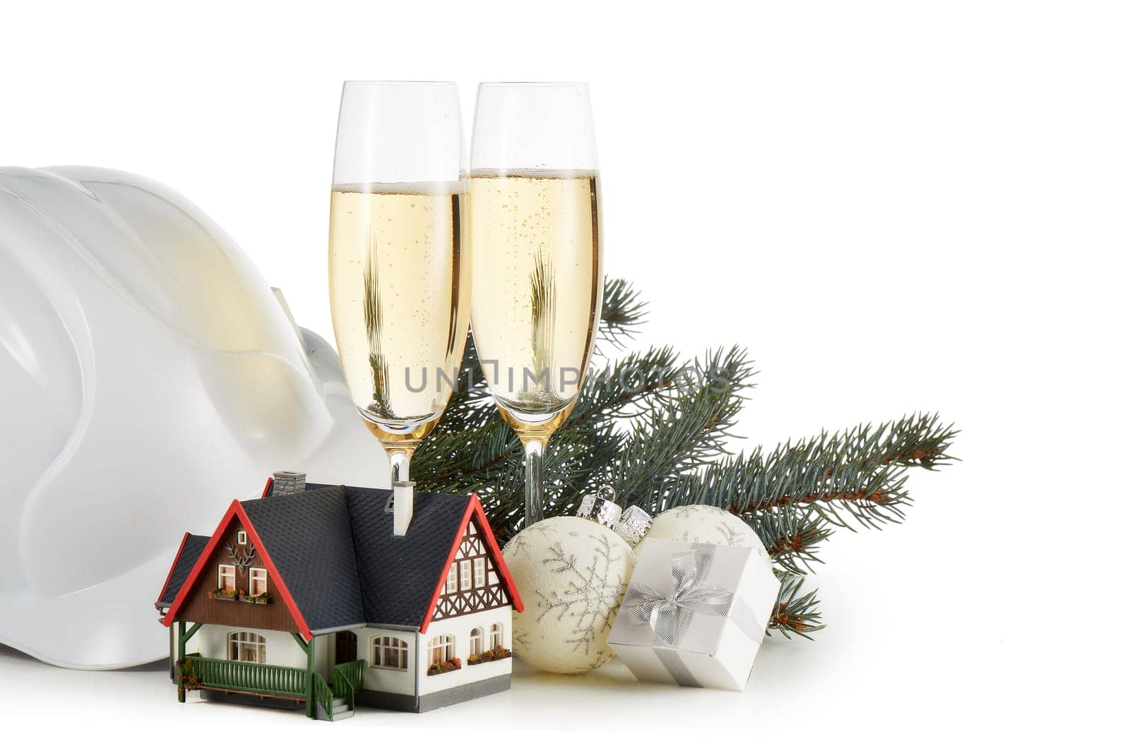 Construction hard hat, fir tree branches, model house, two glasses with champange and Christmas ornament isolated on a white background. New Year and Christmas. Horizontal view with copy space