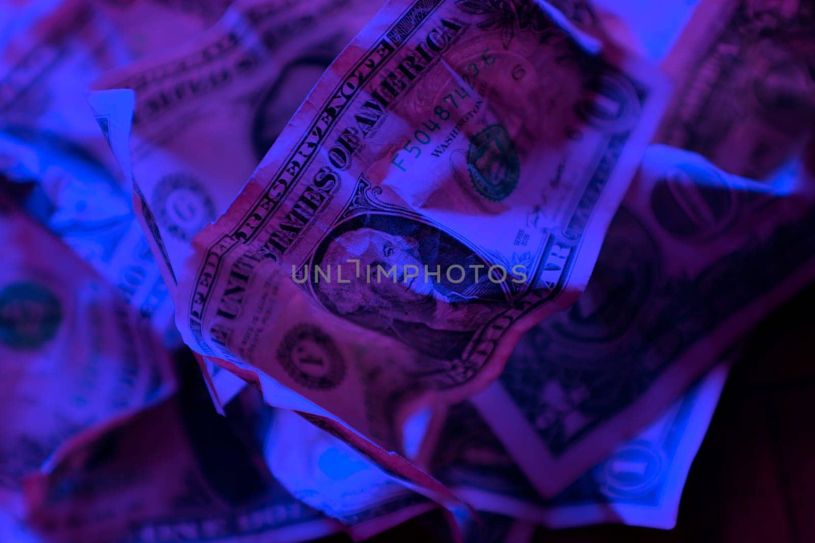 close up wrinkled American one dollar bills under colorful lights