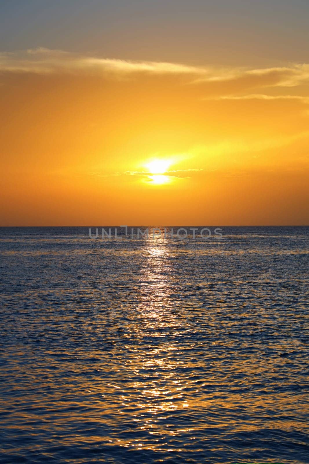 Colorful empty seascape with shiny sea over cloudy sky and sun during sunset in Cozumel, Mexico