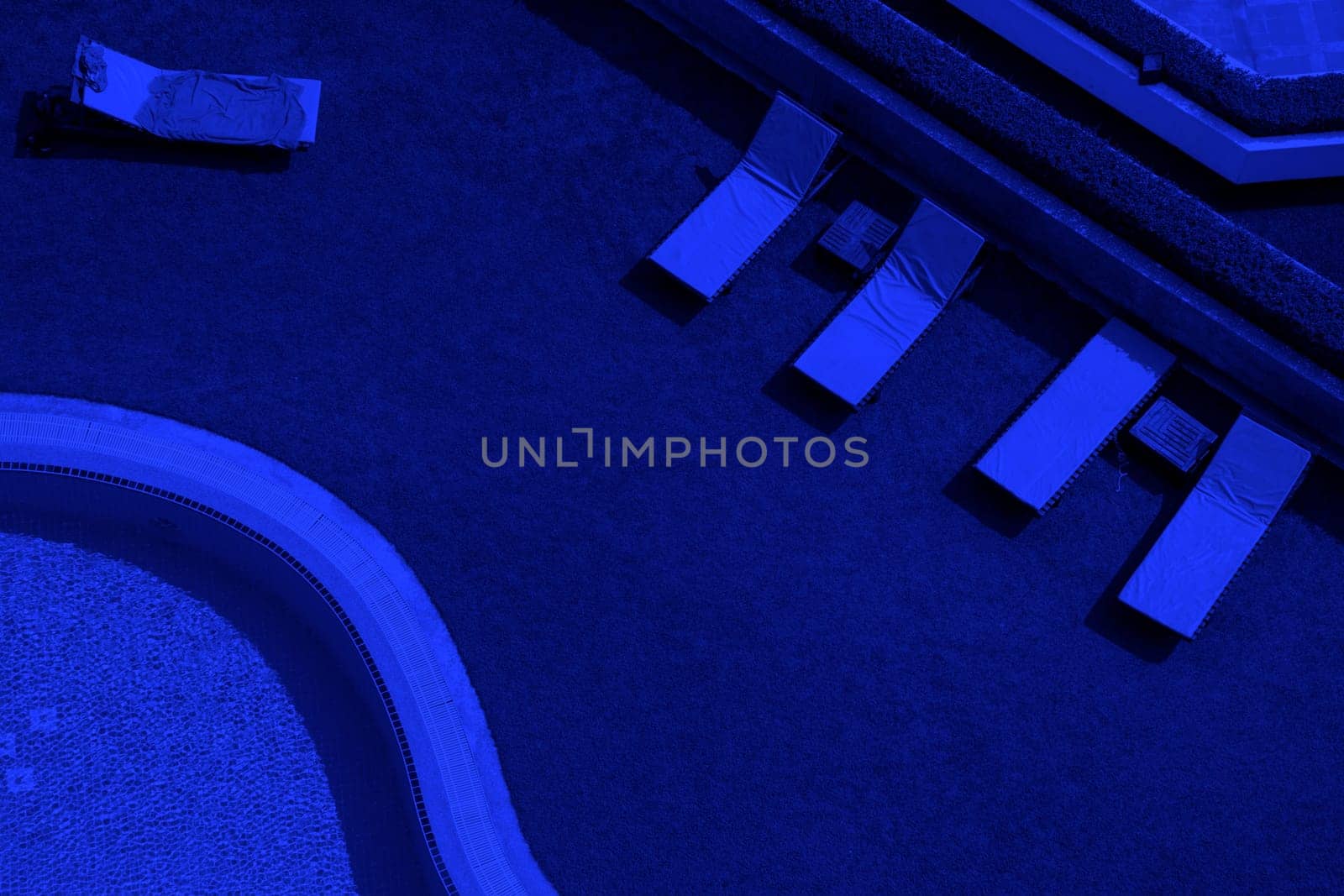 Elevated view of close up outdoor swimming pool and pool chairs with clear clean water