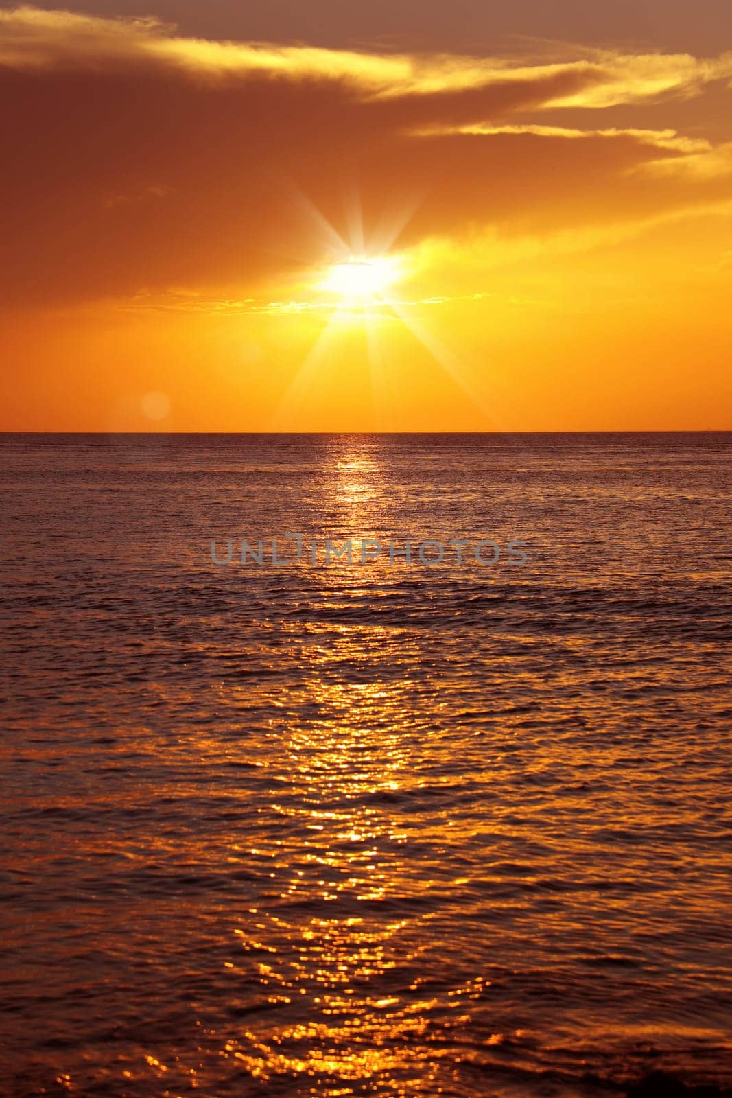 Colorful empty seascape with shiny sea over cloudy sky and sun during sunset in Cozumel, Mexico