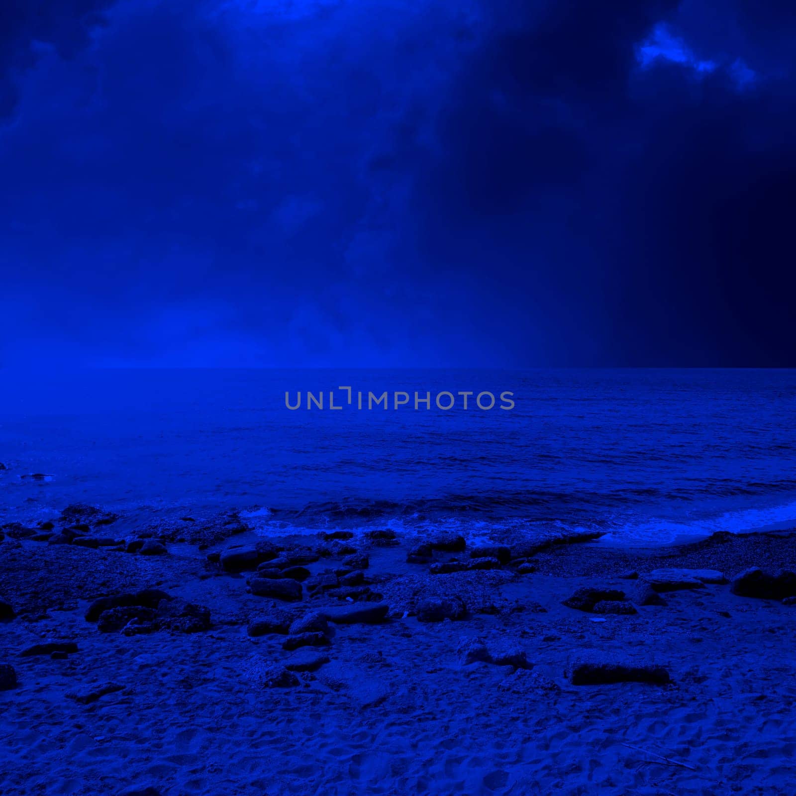 seascape image of sandy and rocky beach over stormy sky
