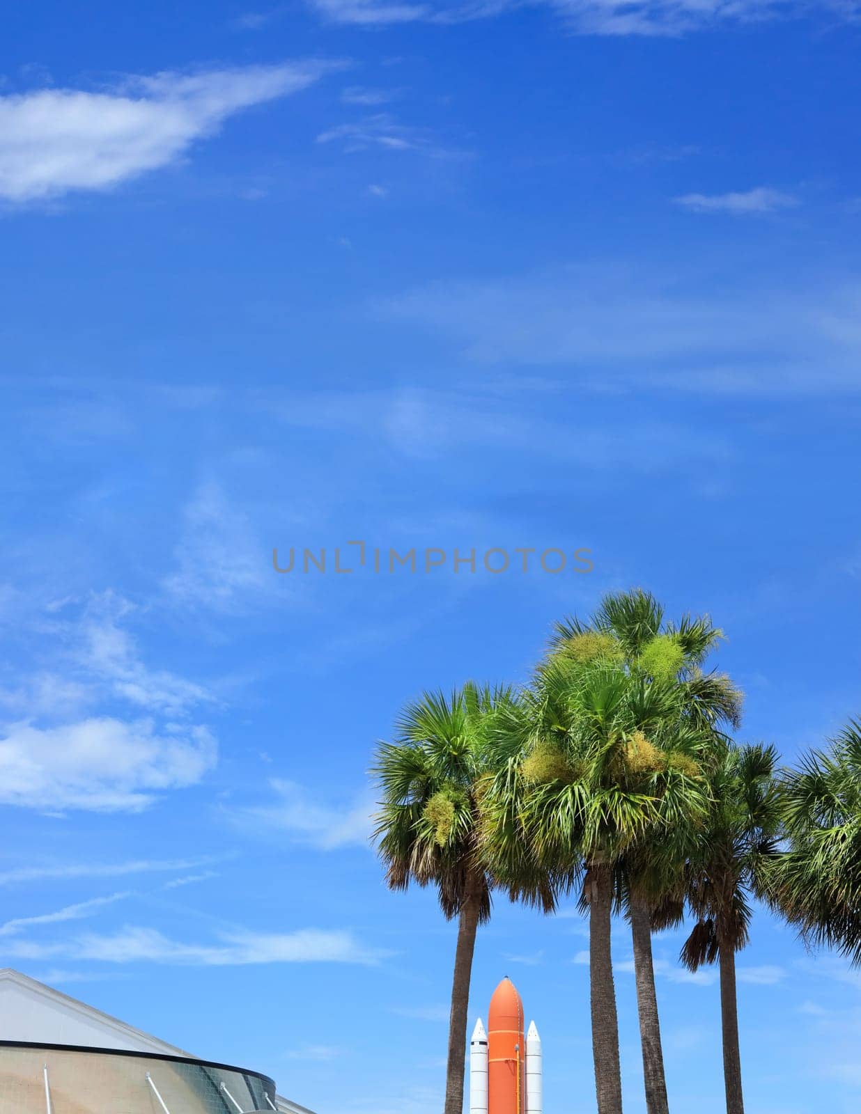 Kennedy space center entrance with space rocket and palm trees over blue sky in Florida, USA