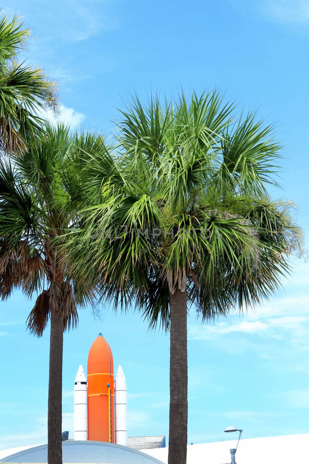 Kennedy space center entrance with space rocket and palm trees over blue sky in Florida, USA