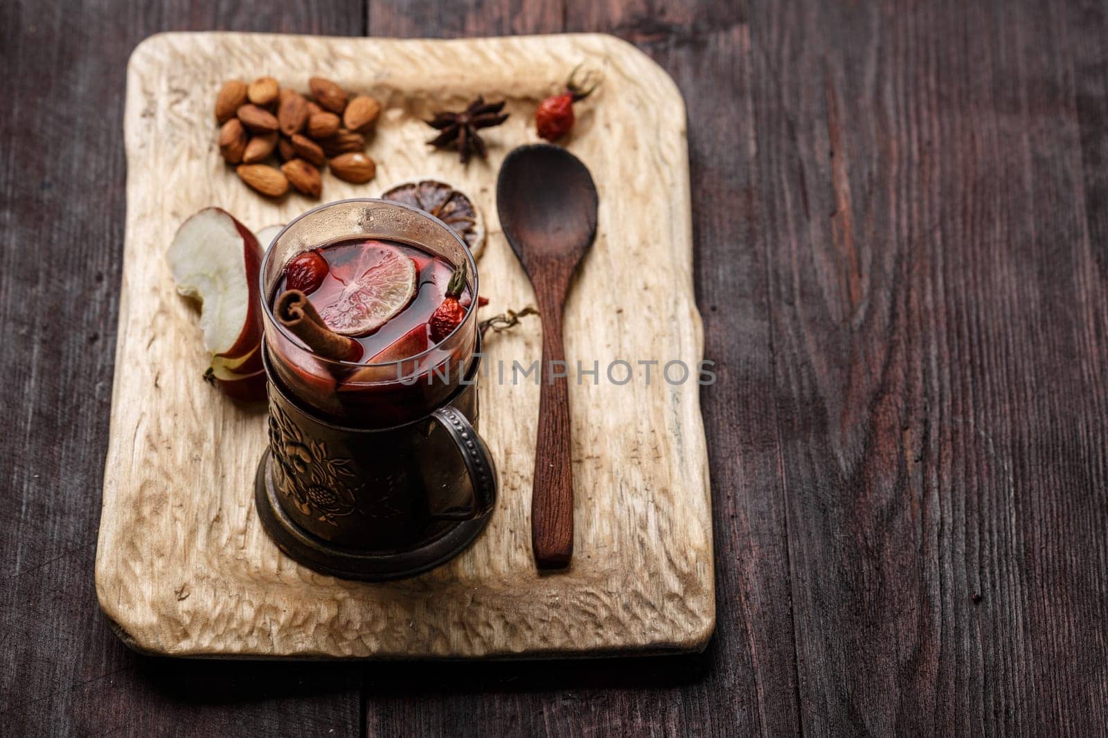 Hot Toddy (mulled wine, punch) with apples and rose hips served on rustic wooden tray with almonds over dark wooden table
