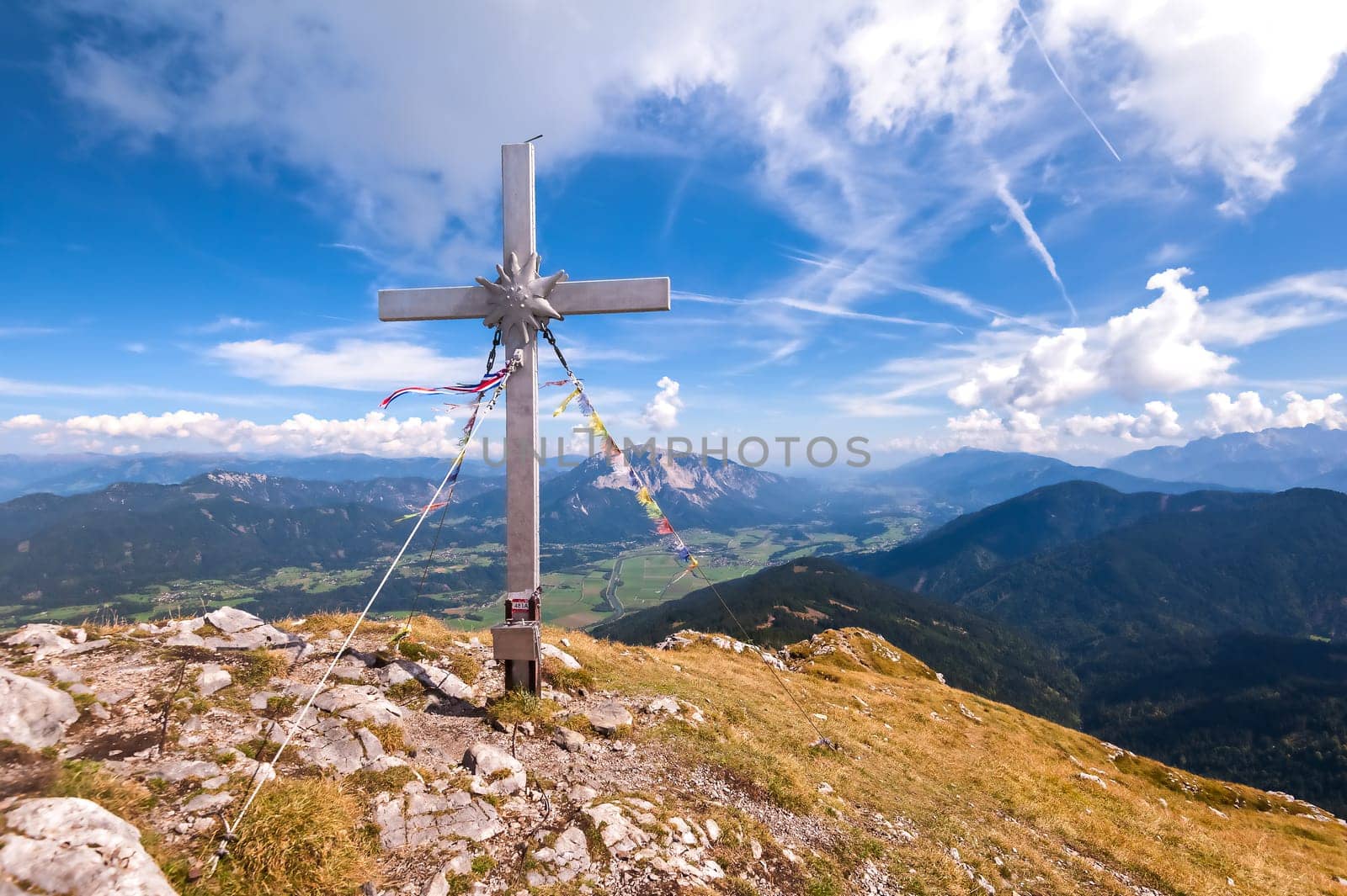 Beautiful mountain panorama with blue sky and clouds, in foreground the cross of top.