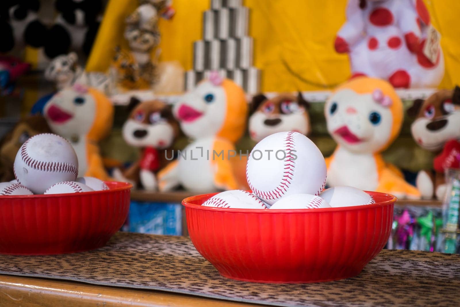 Close-up of baseball balls for the game of throw at jars in a fair. In the background the jars and the prize puppets