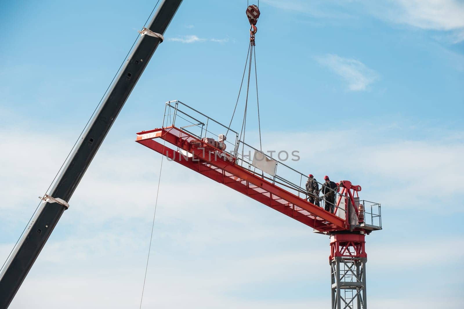 Unrecognizable technicians involved in the assembly of a construction crane.