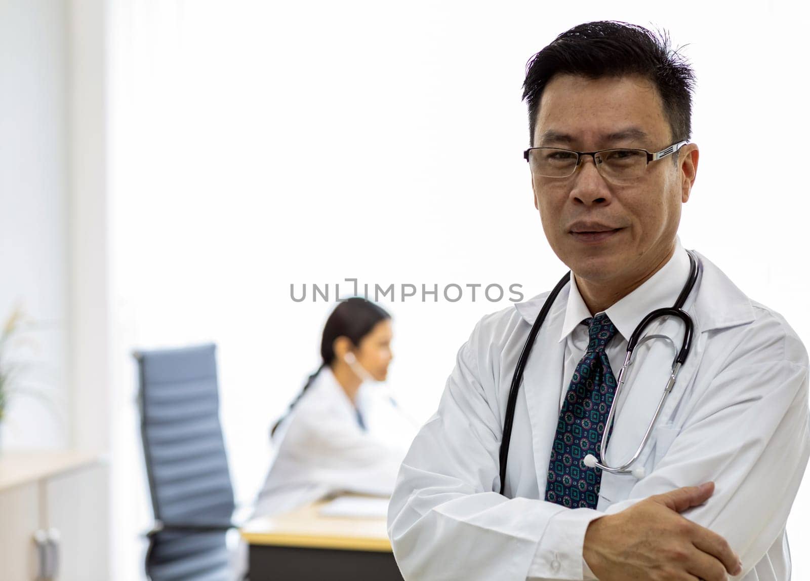 Portrait of senior Doctor in examination room medical office.