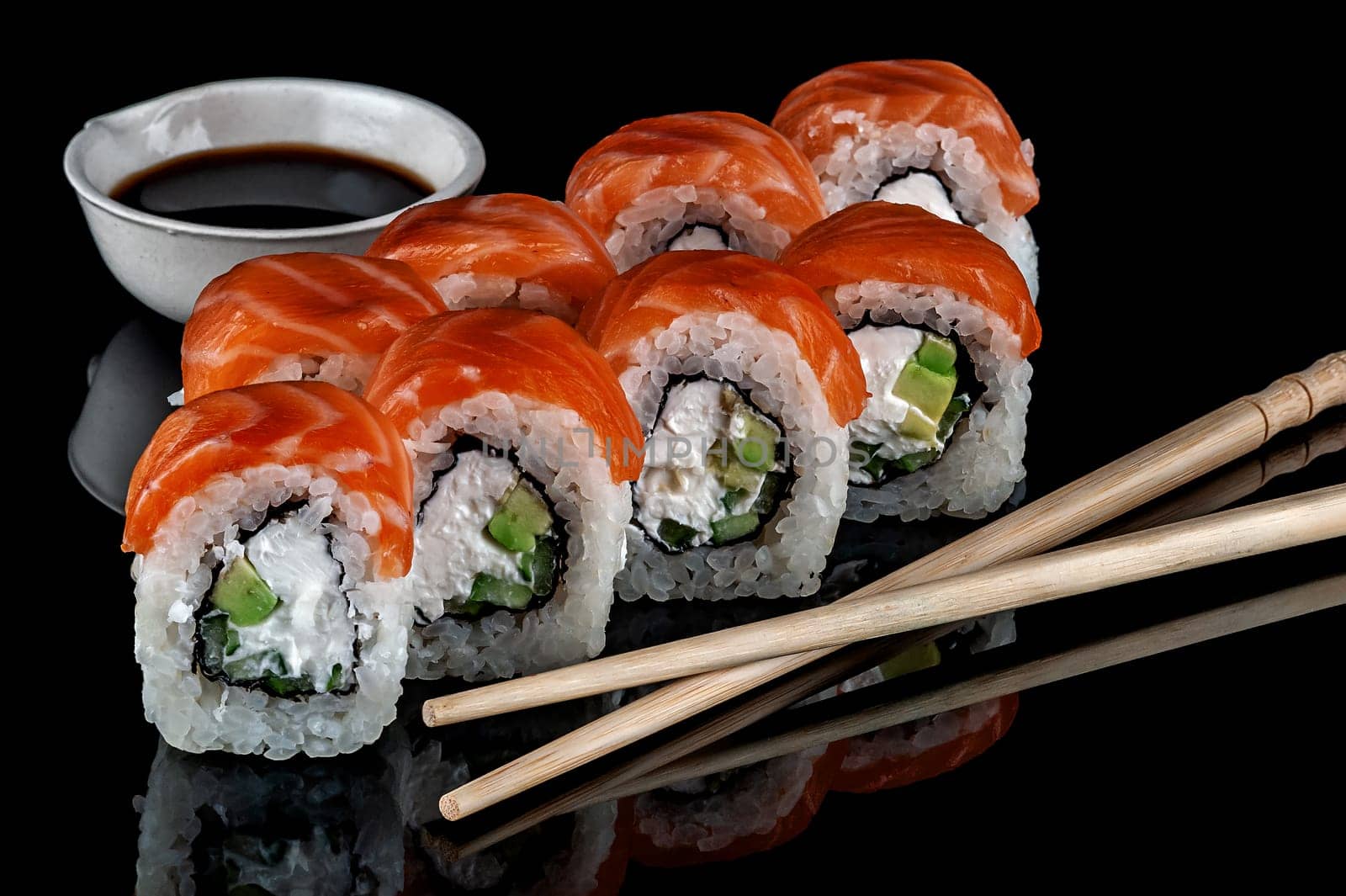 Philadelphia sushi rolls with chopsticks and soy sauce. Black background. Reflection.