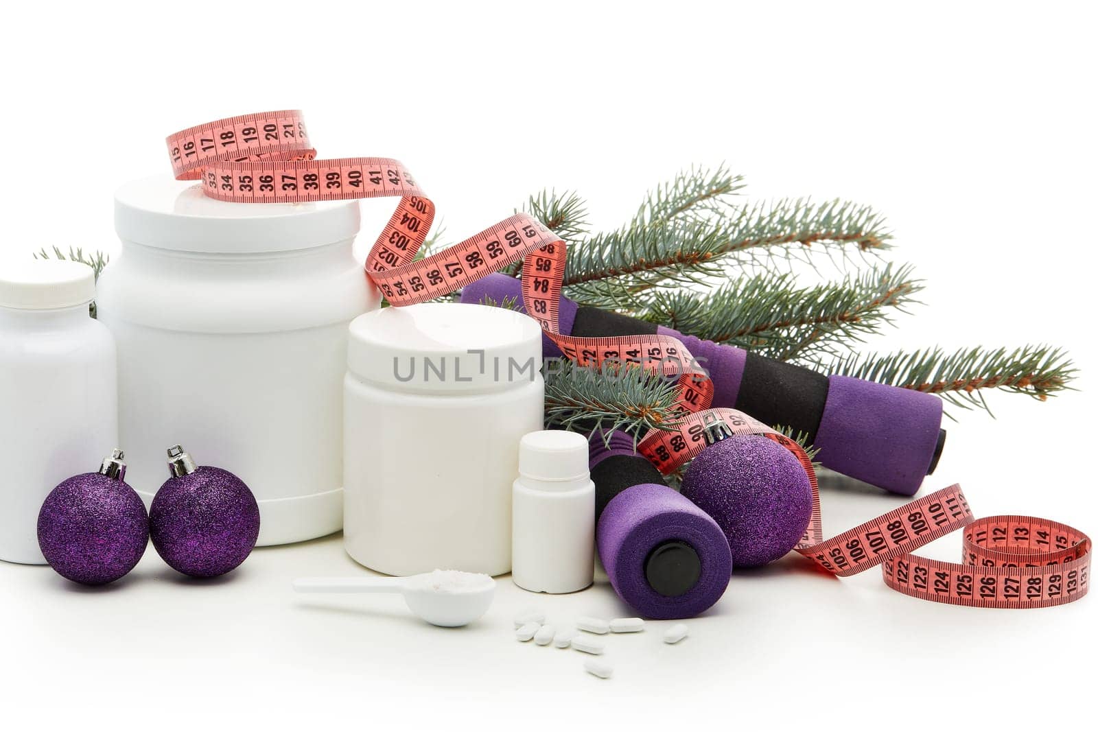 Sports nutrition (supplements), dumbbells, fir tree branches and christmas ormament on a white background. Horizontal view. New Year and Christmas. Fitness. Healthy lifestyle.