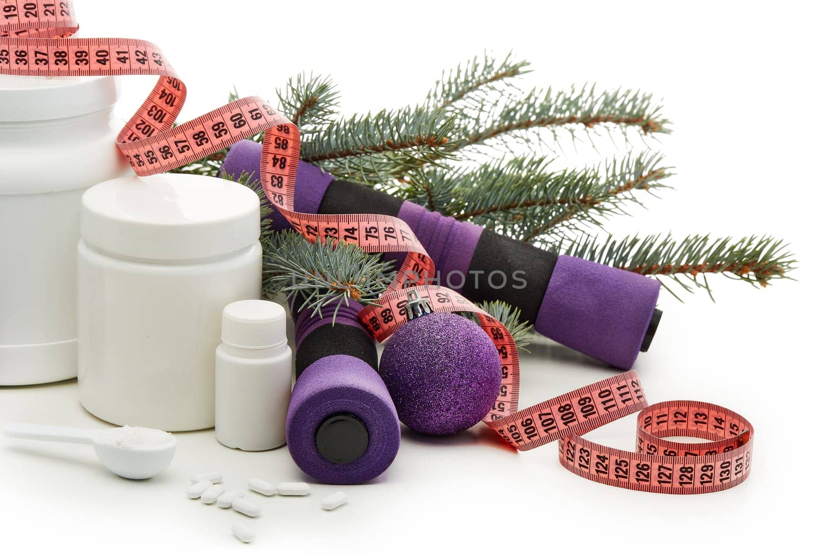 Sports nutrition (supplements), dumbbells, fir tree branches and christmas ormament on a white background. Horizontal view. New Year and Christmas. Fitness. Healthy lifestyle.