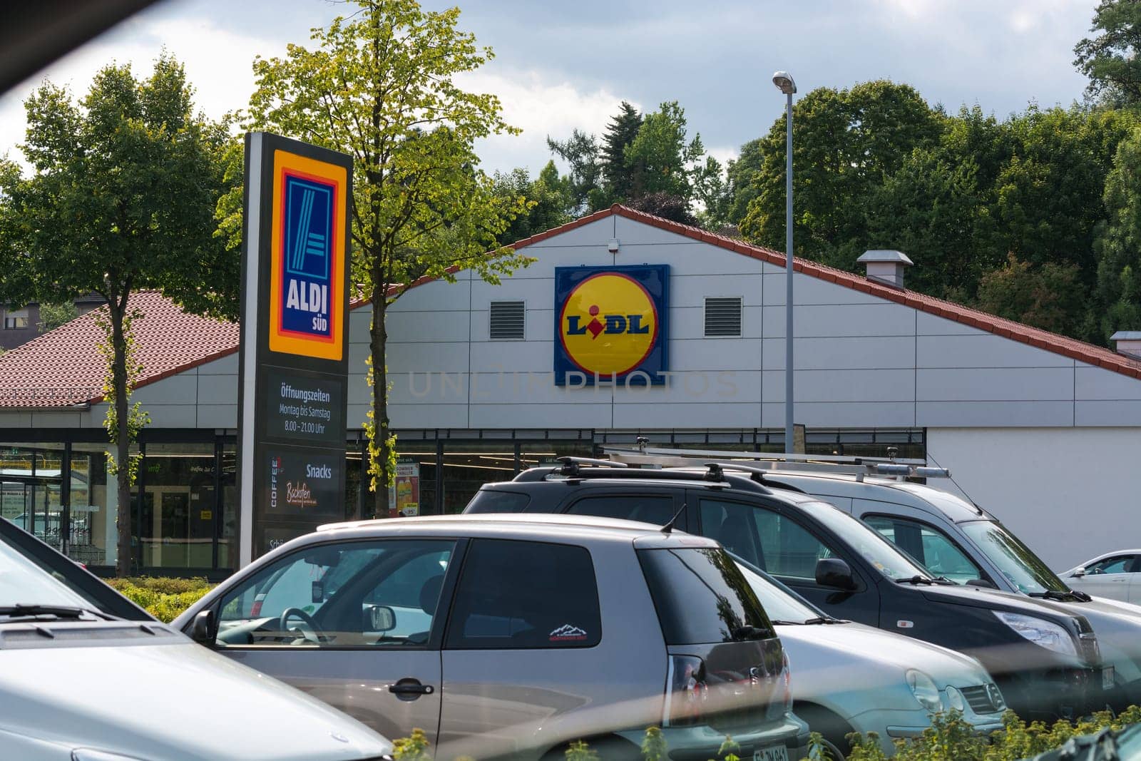 Mülheim Ruhr, Nrw, Germany - June 04, 201k7:Aldi and Lidl supermarket parking lot in Muelheim in Mülheim, Ruhr area, view over the street. A car drives to a parking lot. Outside the supermarket are people.