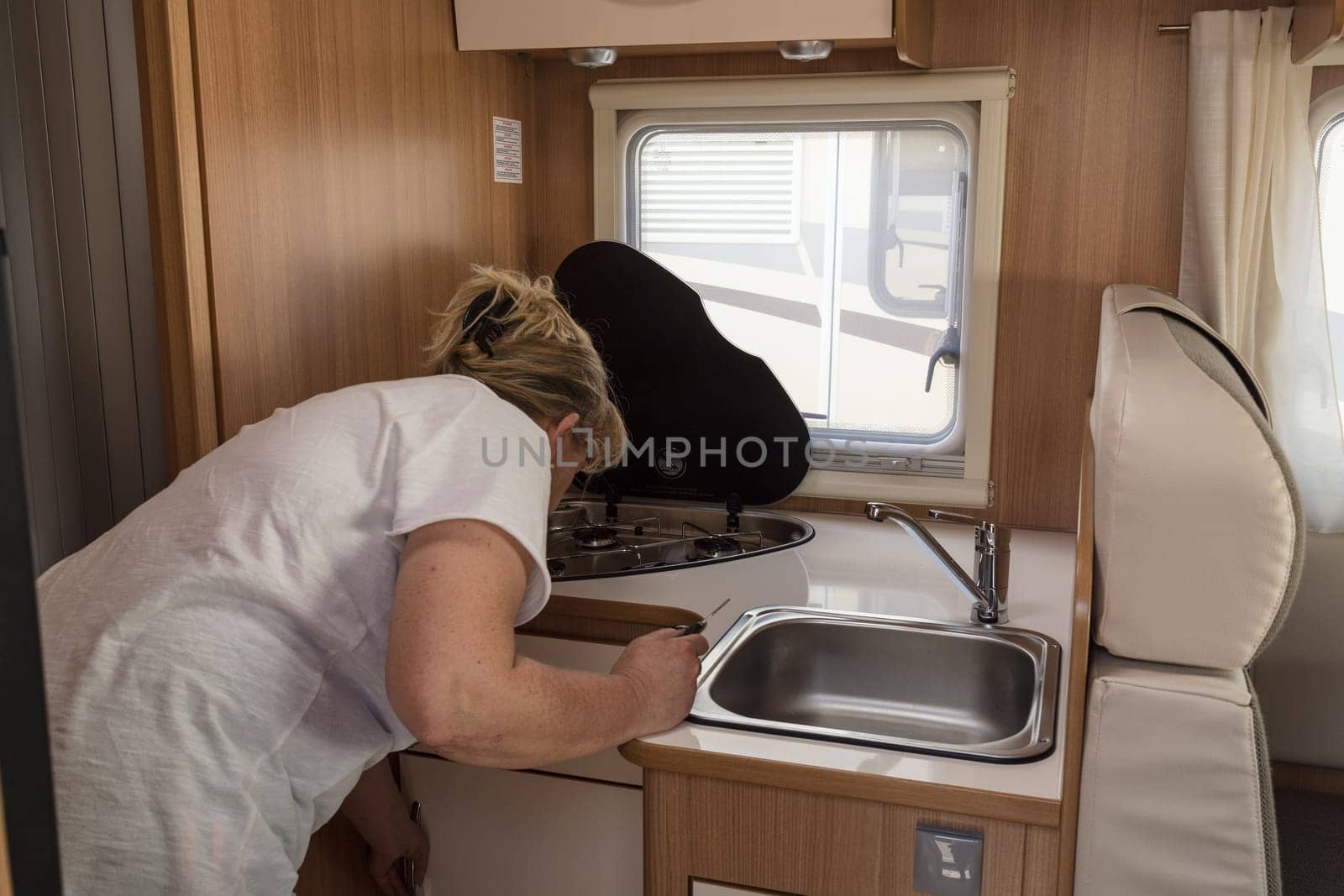 Frau steht gebückt in der Küche von einem Wohnmobil mit Blick in die Küchenschränke...MUELHEIM RUHR  NRW  GERMANY - AUGUST 29  2017:.Woman stands bent in the kitchen by a camper with a view of the kitchen cabinets.