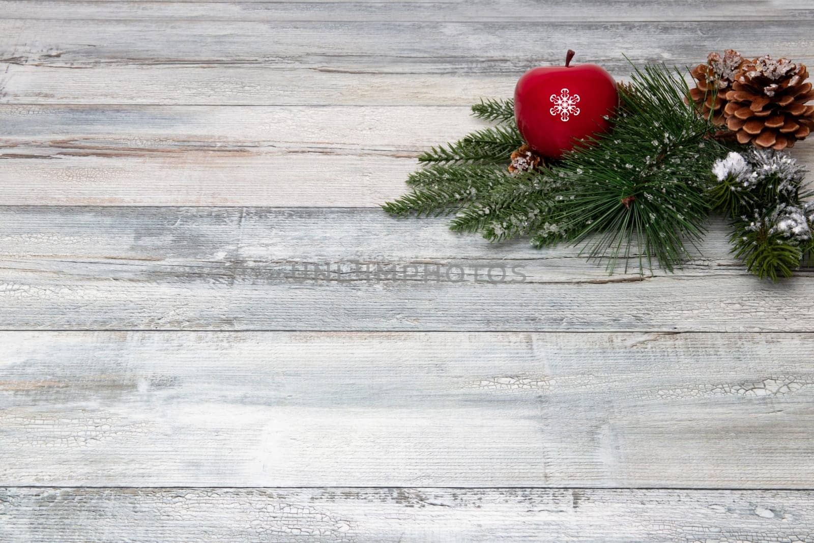 Christmas or Happy New Year decoration background. Composition from sparkling christmas tree branches with a red apple and fir cones on a rustic wooden background. Top view copy space.