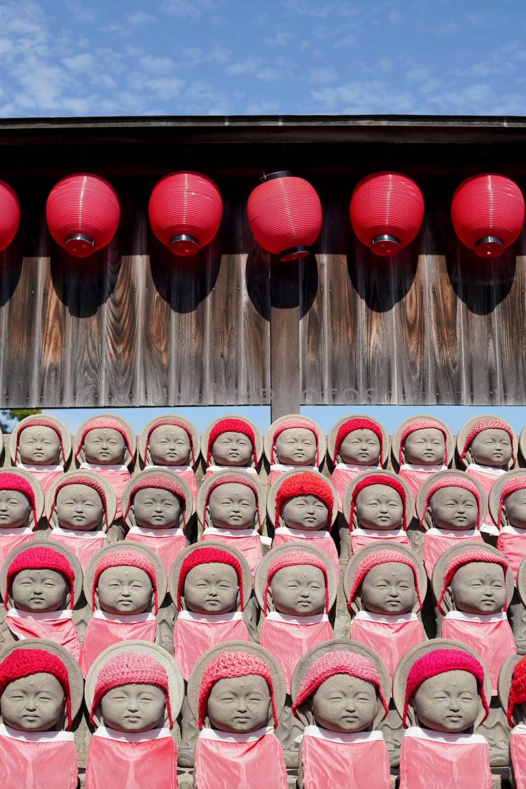 Row of buddhist mizuko jizo statues with red bib, hat