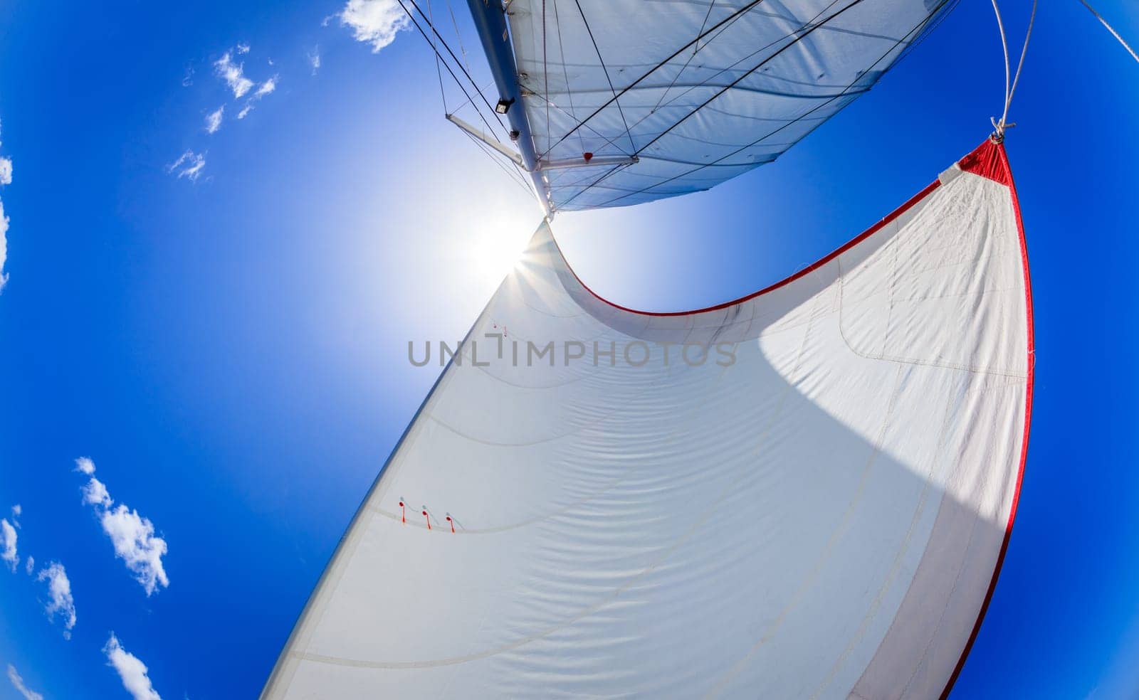 Fisheye image of sails against blue skies and the sun