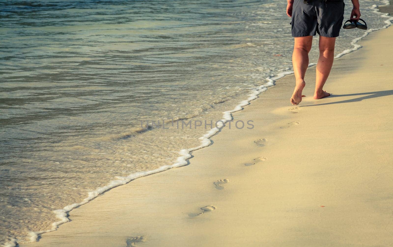 A person walkng along a sand beach on an island in BVI