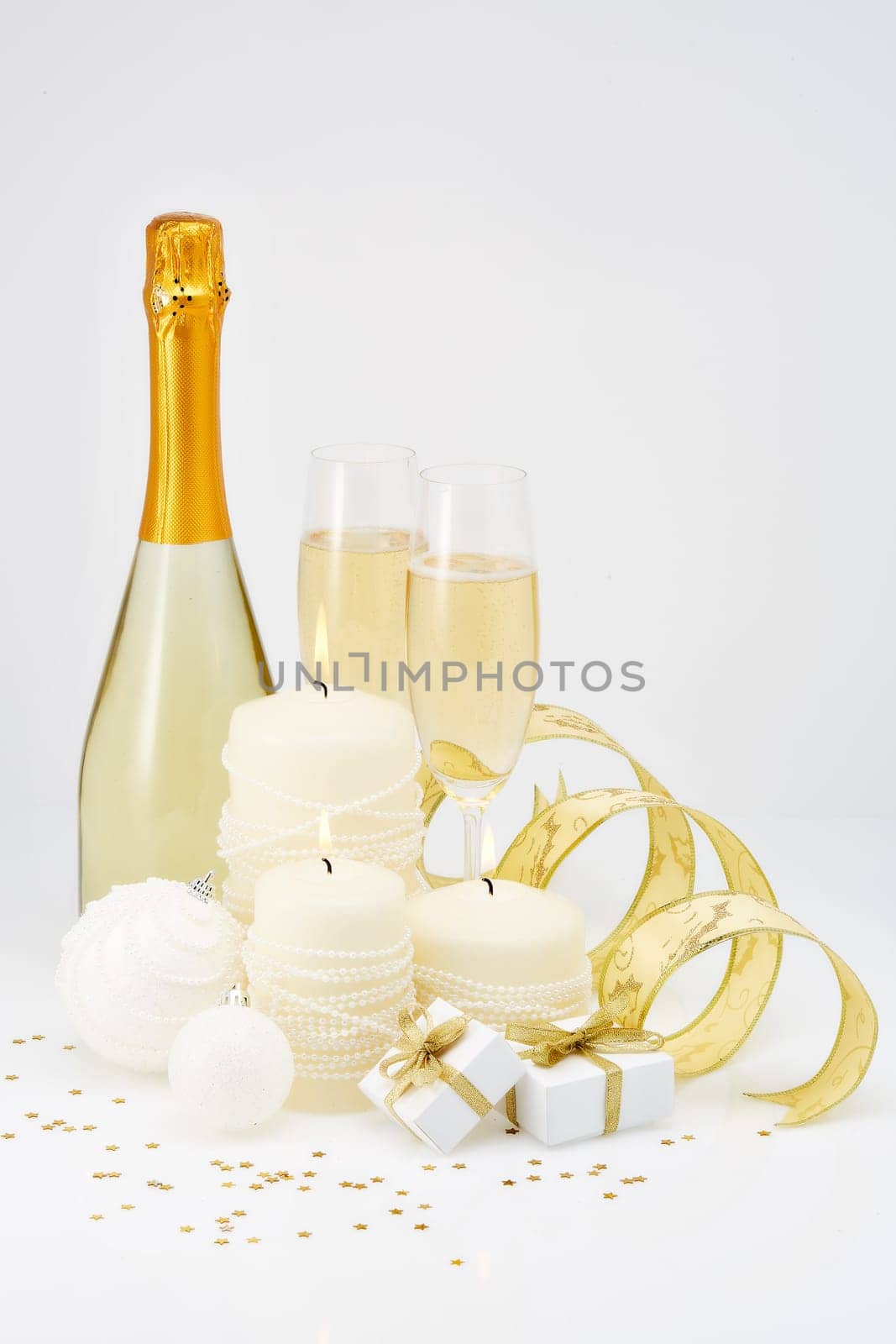 Christmas and New Year still life with two wineglasses of champagne, bottle, gift boxes and Christmas ornaments isolated on a white background. Christmas and New Year greeting card