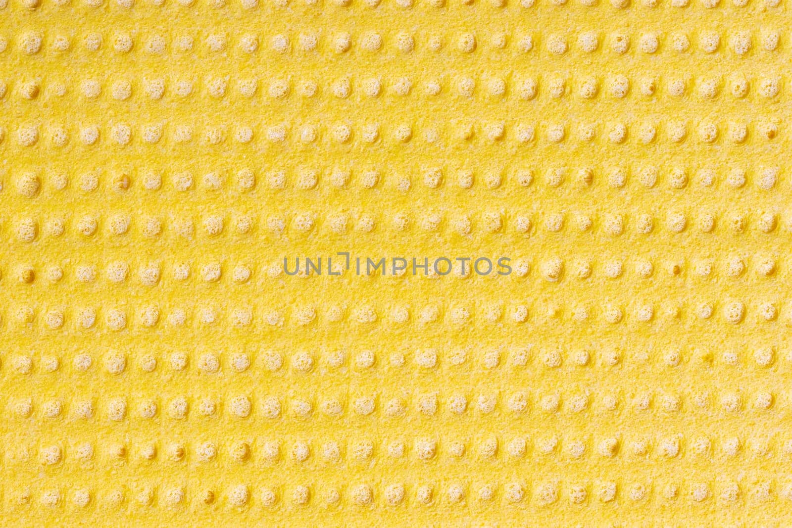 Cleaning cloth. Closeup of bright yellow viskose cleaning rag. Pattern yellow background or backdrop. Macro.