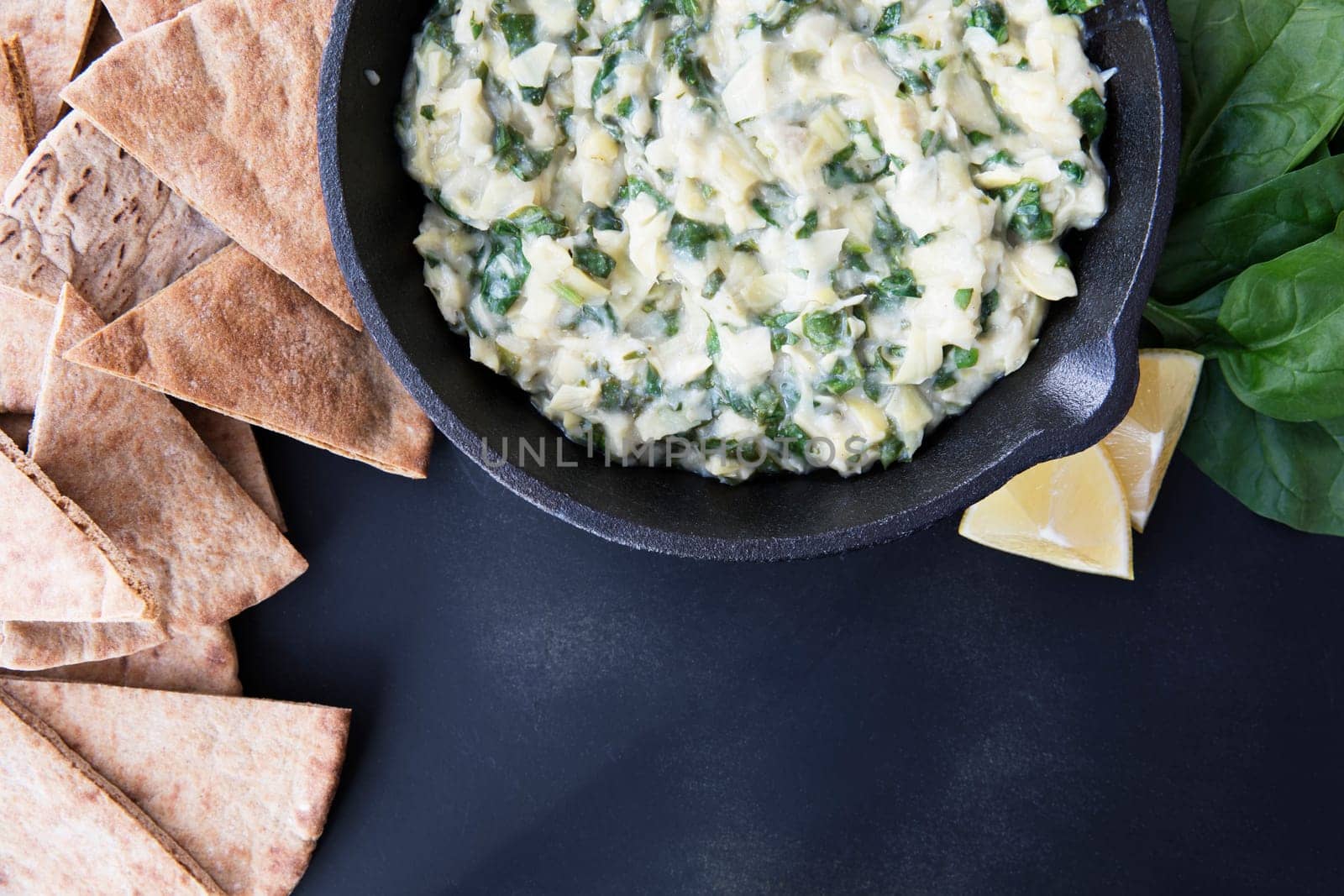 Pan with fresh vegan spinach artichoke dip and whole wheat pita bread.