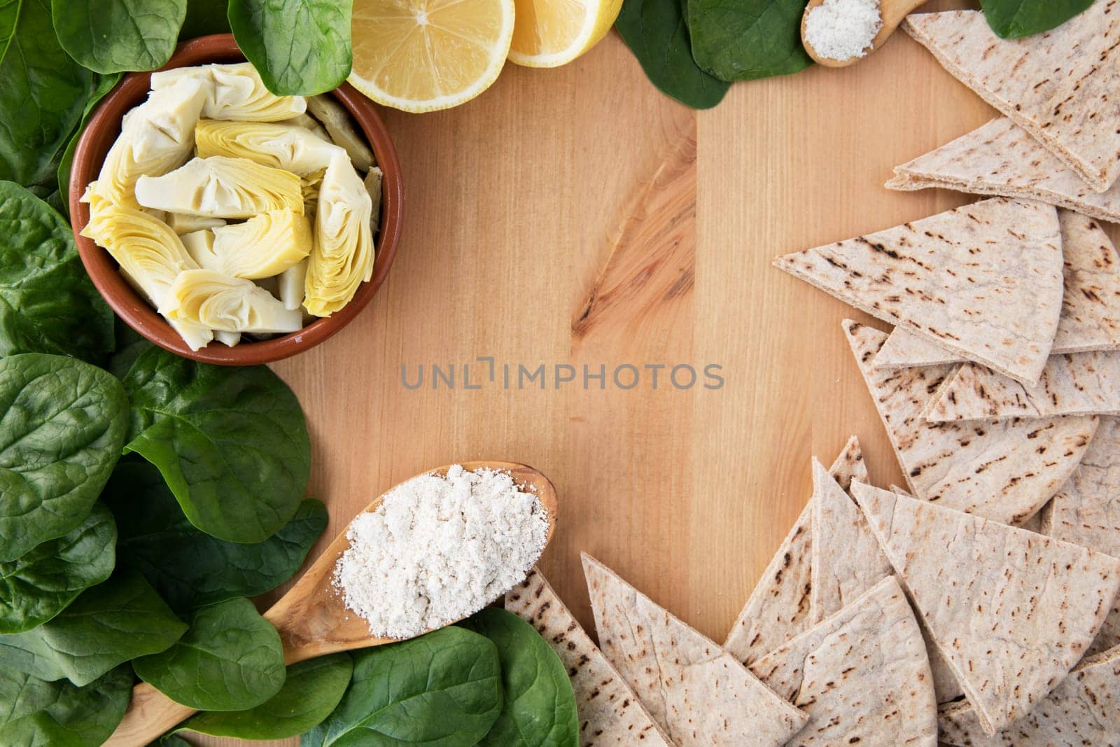 Artichoke hearts, spinach, lemon and other ingredients for vegan dip flat lay with copy space
