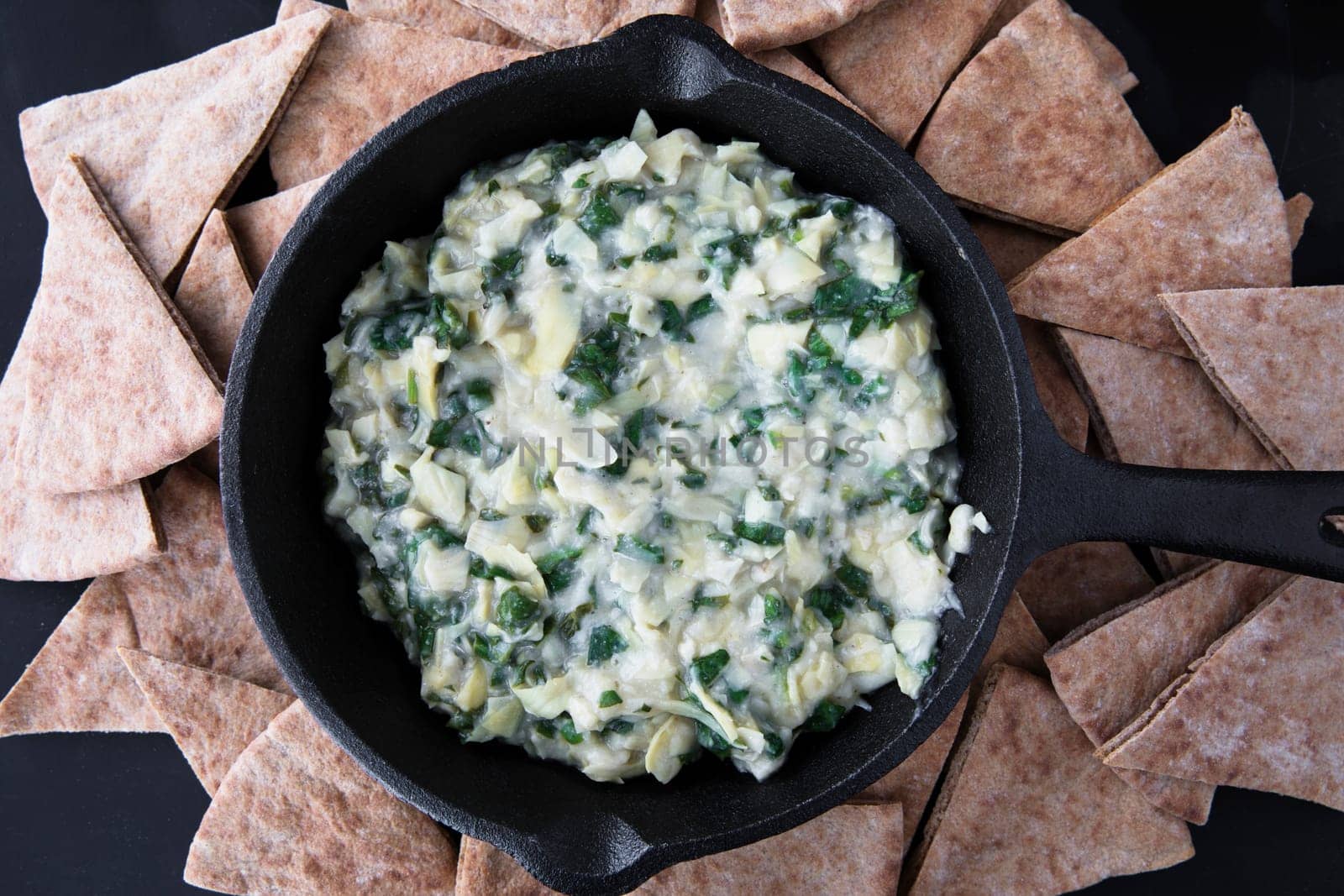 Pan with fresh vegan spinach artichoke dip and whole wheat pita bread.