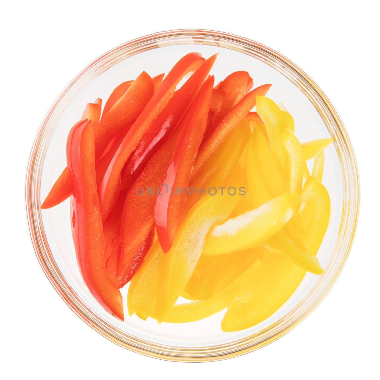 Sliced red and yellow peppers in a glass bowl, isolated on white and viewed from above.