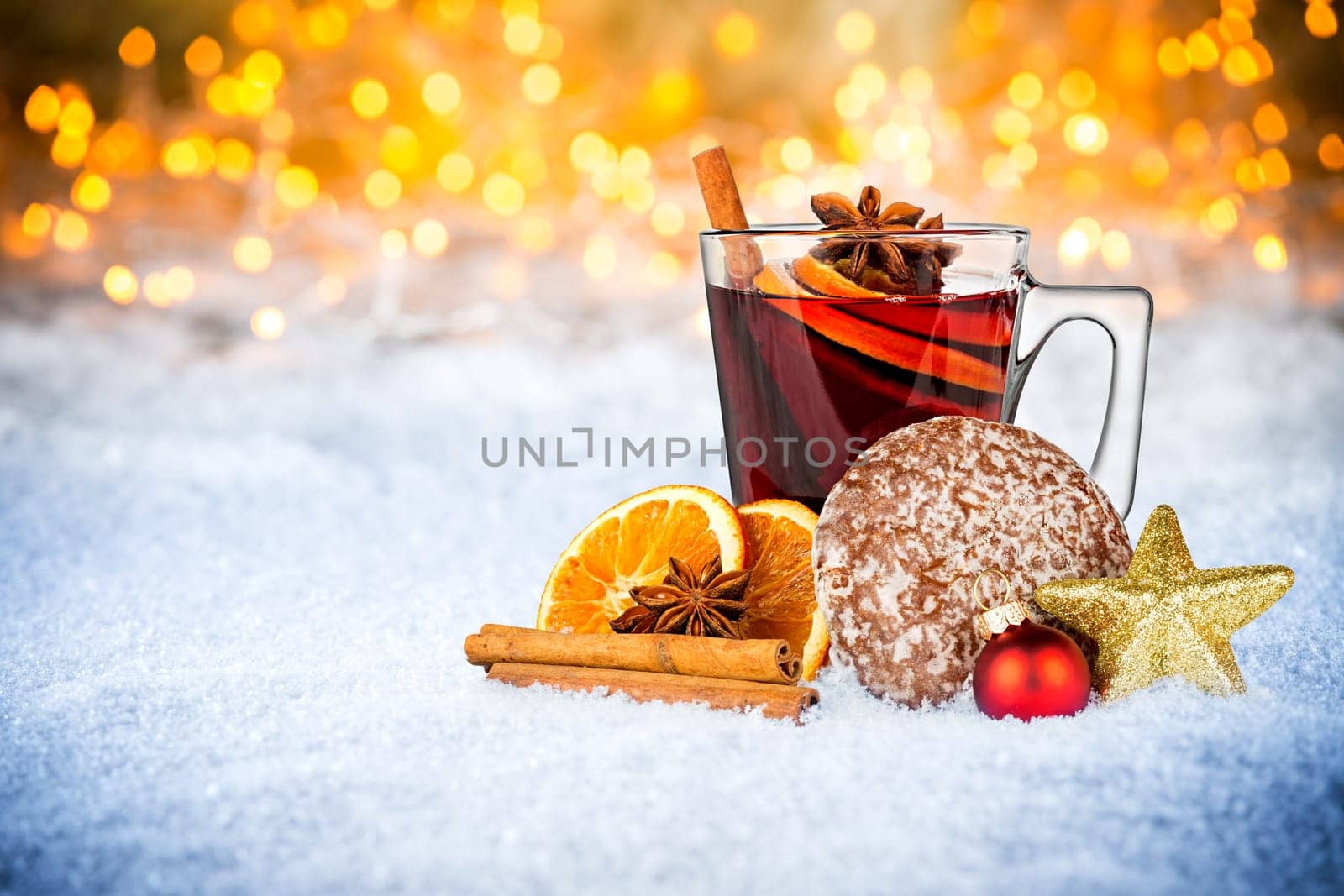 hot mulled spiced red wine in glass mug with gingerbread orange slice christmas xmas decoration illuminated bright lights bokeh background