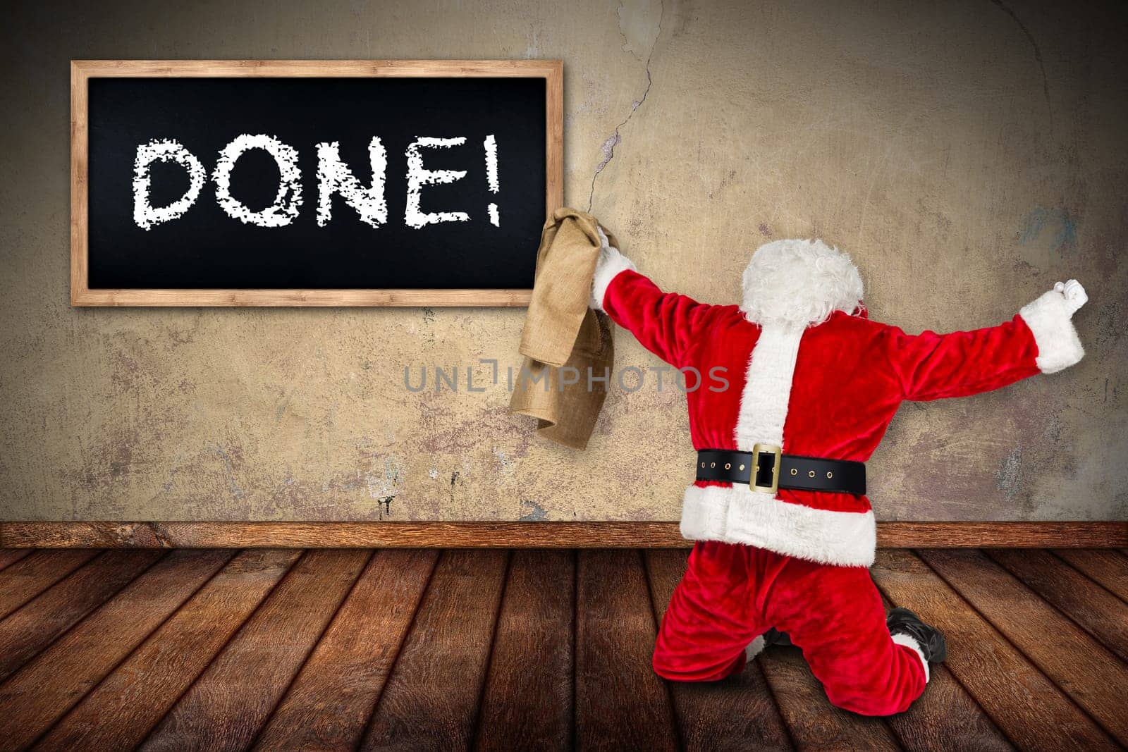 funny crazy hilarious red white santa claus celebration clench fist holding bag in the air job done blackboard on wooden floor interior room