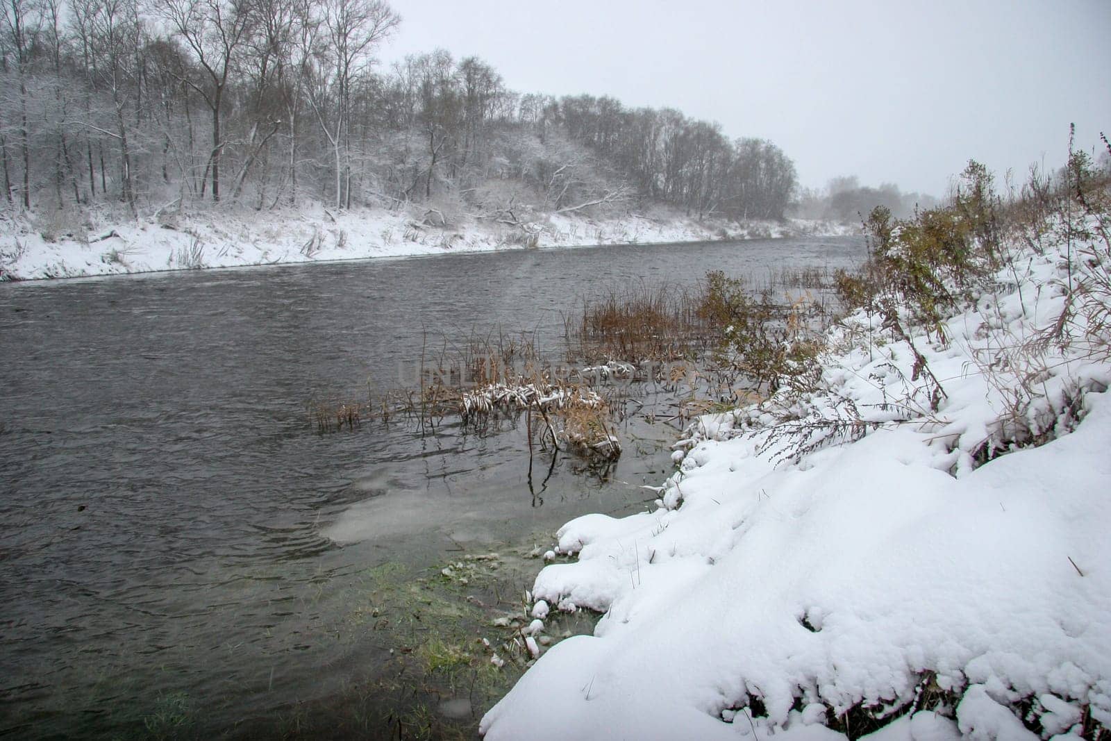 River landscape in winter. River with snow-covered coasts. River Memele in snowfall time. Winter in Latvia. Snow covered landscape with forest and riwer during the winter. ..